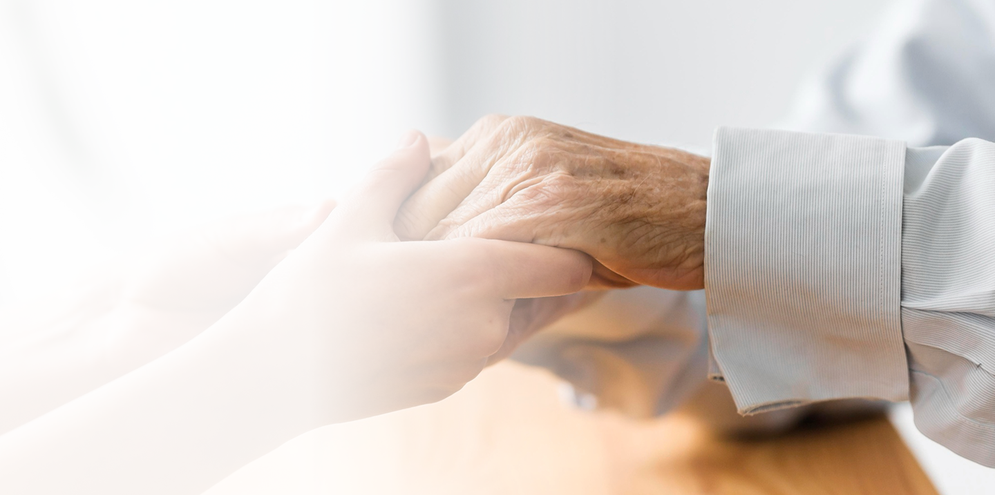 Hands of a caregiver gently holding the hand of an elderly person, symbolizing support and compassion in Medicare assistance.