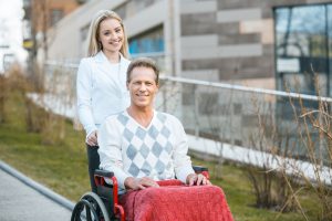 Smiling caregiver assisting a man in a wheelchair, representing support for individuals with disabilities related to Medicare.