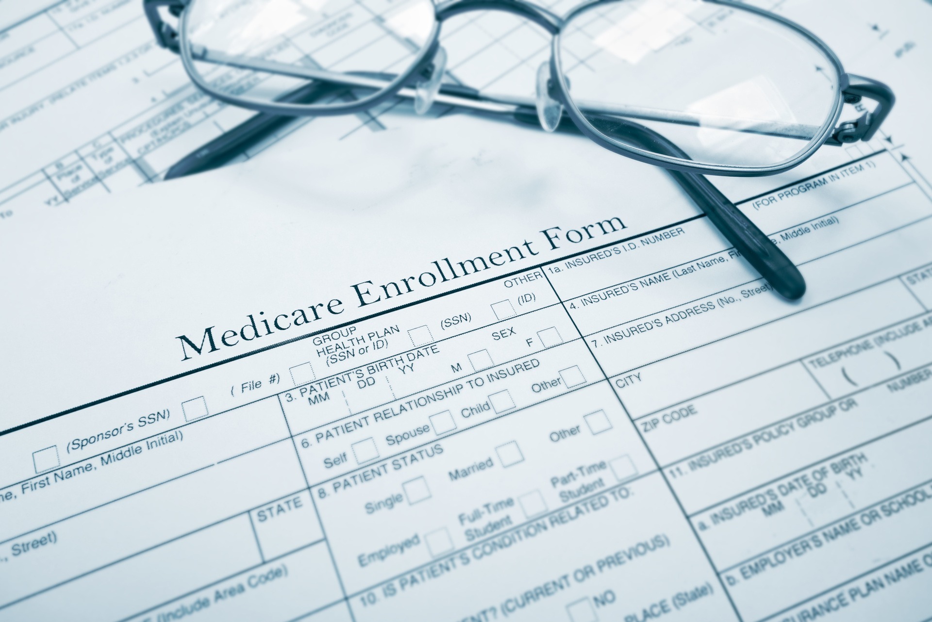 Medicare enrollment form with glasses and pen, illustrating the signing up process for Medicare.