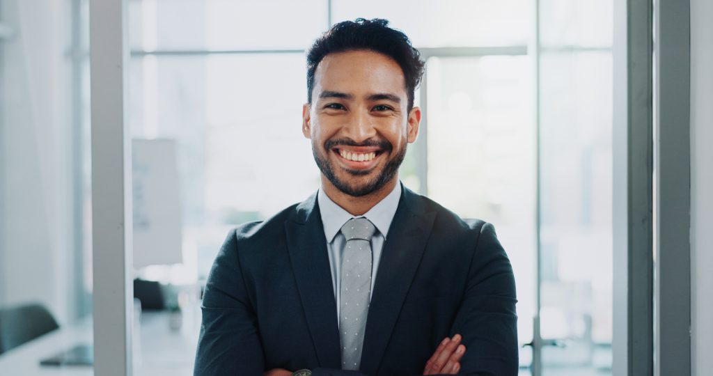 Smiling professional man in a suit, representing expertise in health insurance and financial planning services.