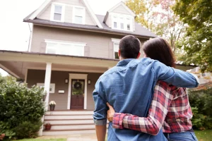 Couple embracing in front of a house, symbolizing homeownership and financial planning related to Medicare and prescription drug coverage.
