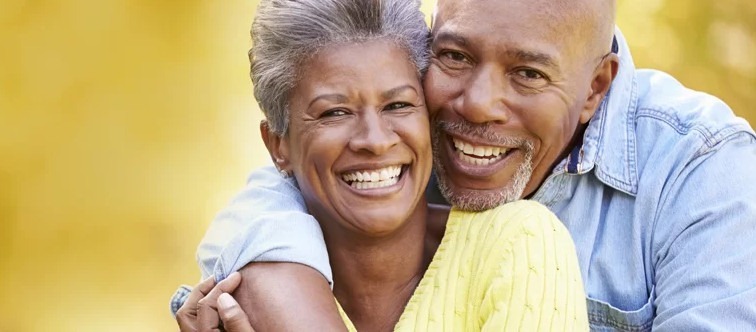 Smiling senior couple embracing outdoors, representing joy and companionship in the context of Medicare and financial planning for seniors.