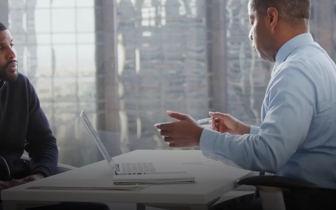 Client discussing financial planning options with an insurance agent at a desk featuring a laptop, emphasizing retirement solutions and fixed annuities.