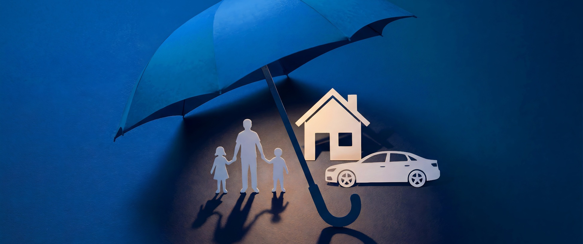 Paper cutout family under an umbrella, symbolizing protection, with a house and car, representing umbrella insurance coverage for personal assets.