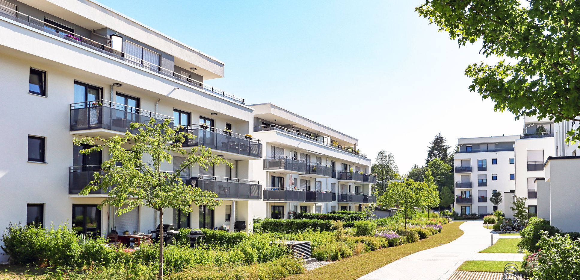 Modern apartment complex with balconies, surrounded by greenery and pathways, illustrating rental living options relevant to renters insurance guidance.