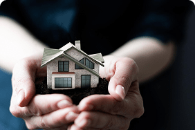 Hands holding a small house model, symbolizing homeowners insurance and property protection in Florida.