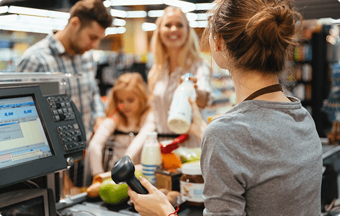 Cashier scanning items at a grocery store with customers in line, highlighting consumer interactions and shopping experience.