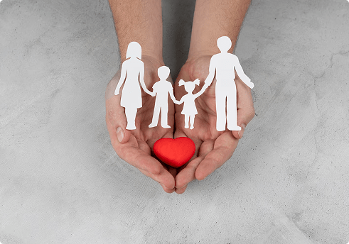 Hands holding a red heart with cut-out figures of a family, symbolizing life insurance protection and family security in Florida.