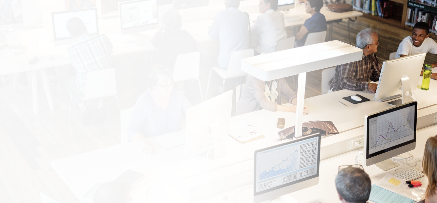 Group of professionals collaborating in a modern office setting, analyzing data on computers, emphasizing teamwork and productivity related to workers' compensation insurance services.