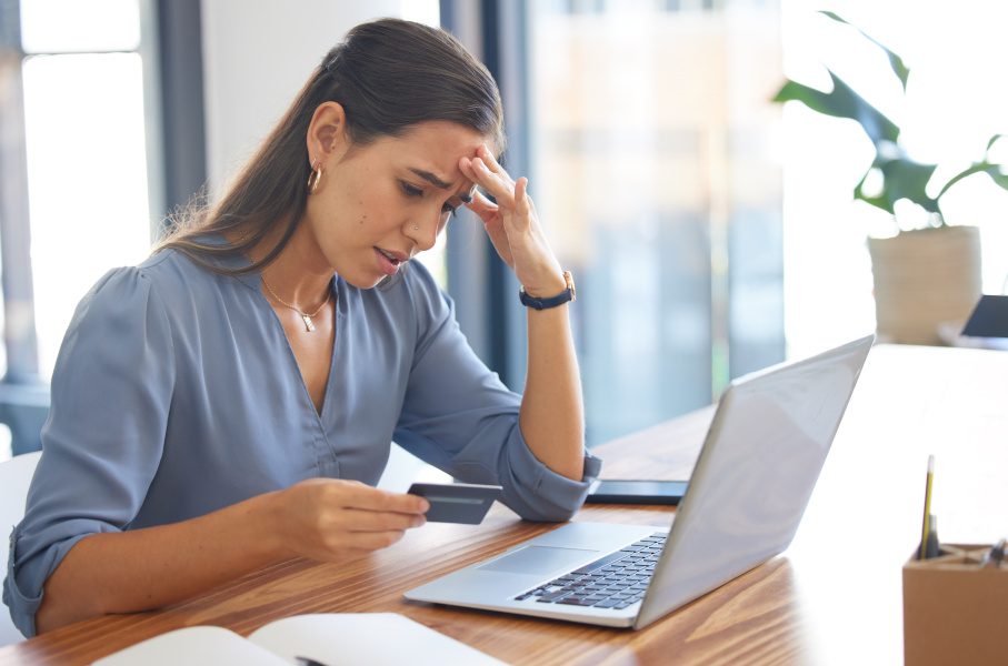 woman on pc looking at credit card with concern
