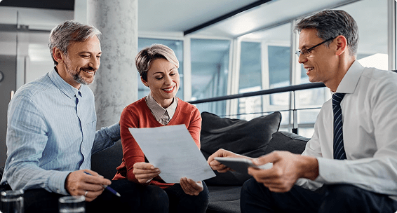 Couple discussing insurance options with advisor, reviewing documents in modern office setting.