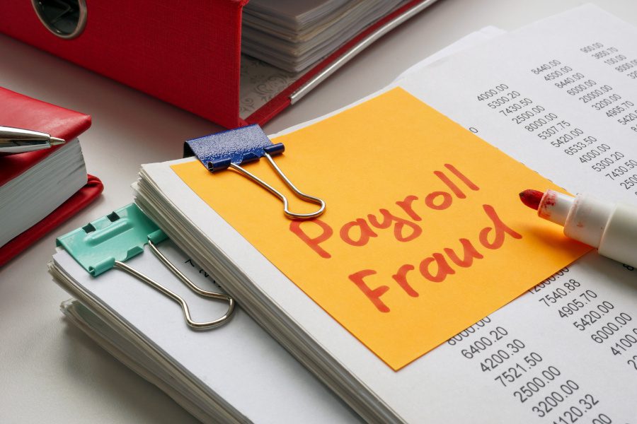 stack of papers with a sticky not saying payroll fraud
