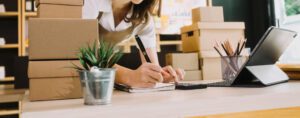 Small Business owner doing paperwork with boxes on her desk