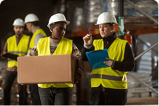 worker carrying a box talking to another worker